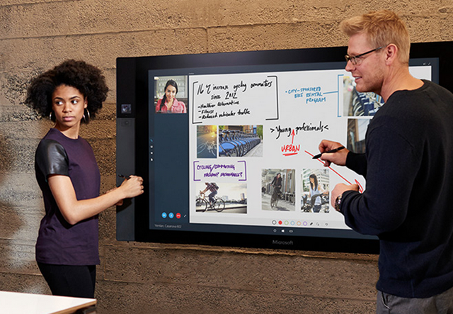 Two people working on a Microsoft Surface Hub